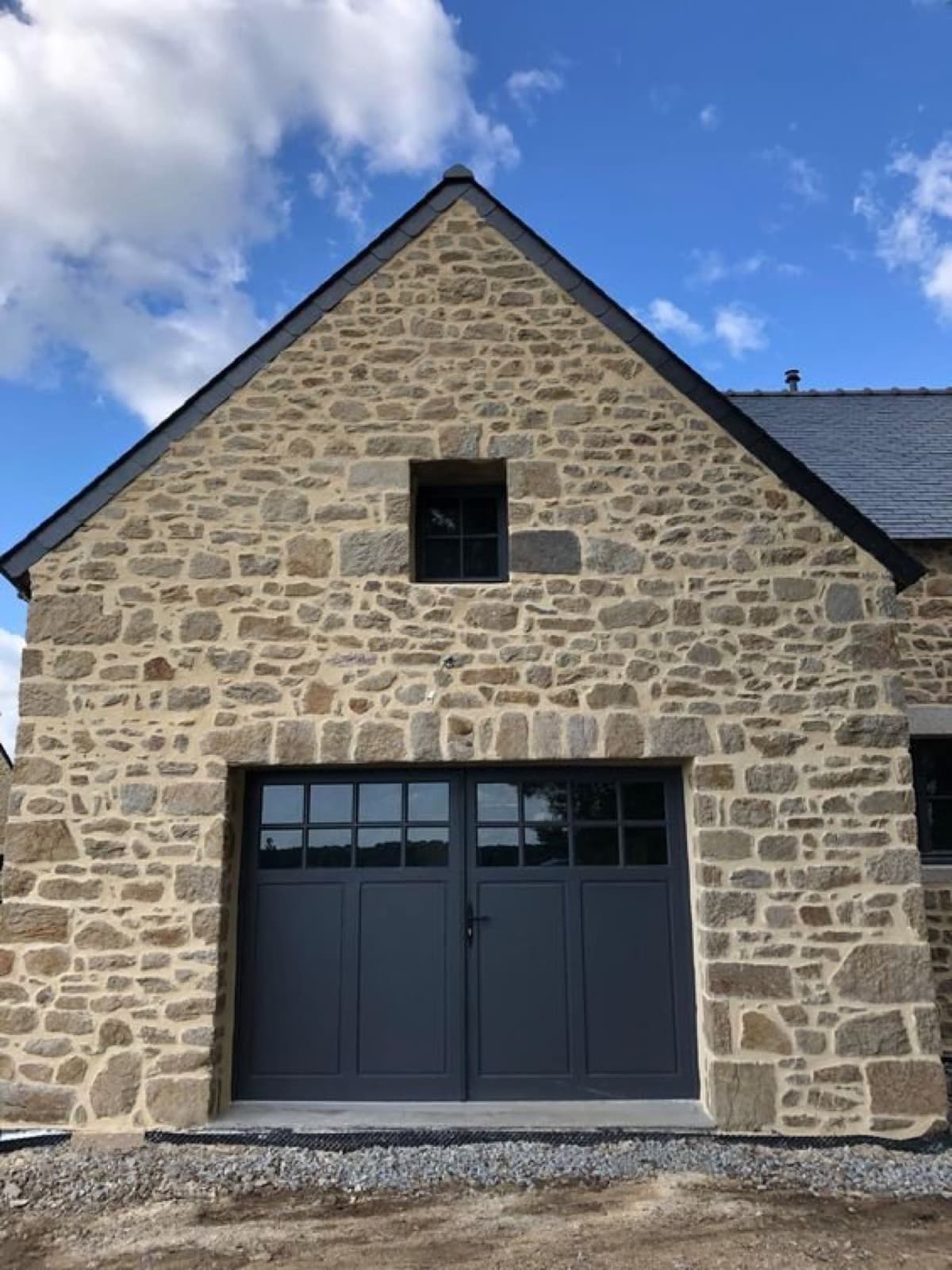 Porte de garage battante gris anthracite sur une maison en pierre à Figeac